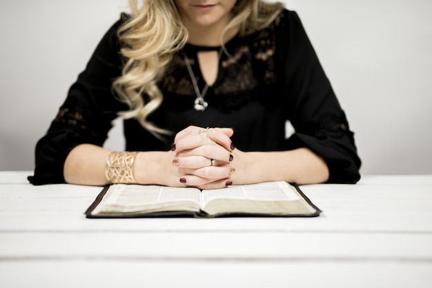 Femme blonde lisant une bible sur la table