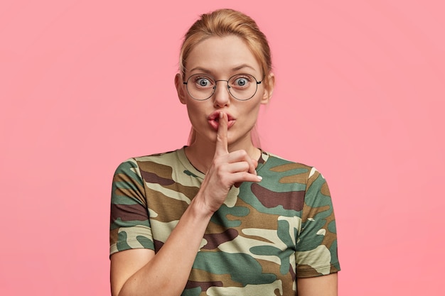 Femme blonde à lunettes rondes et t-shirt camouflage