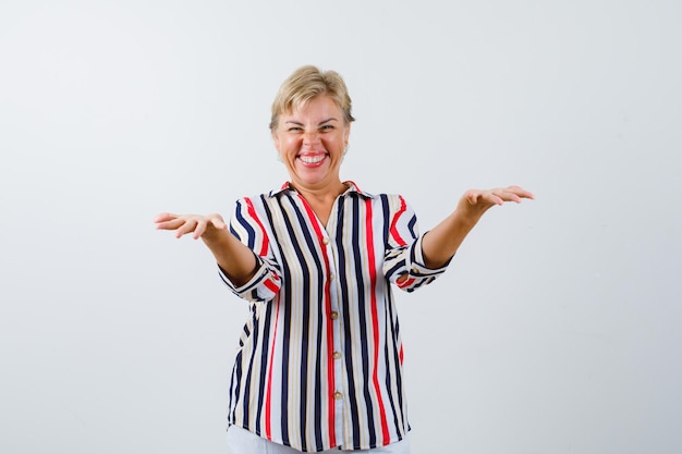 Femme blonde mature dans une chemise à rayures verticales