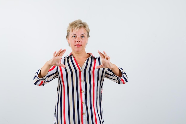 Femme blonde mature dans une chemise à rayures verticales