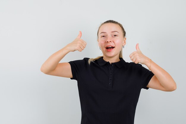 Femme blonde montrant les pouces vers le haut en t-shirt noir et à la recherche de plaisir