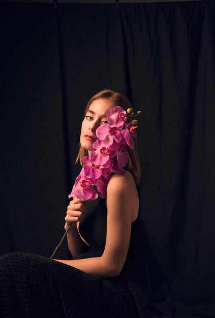 Femme blonde pensive avec fleur rose