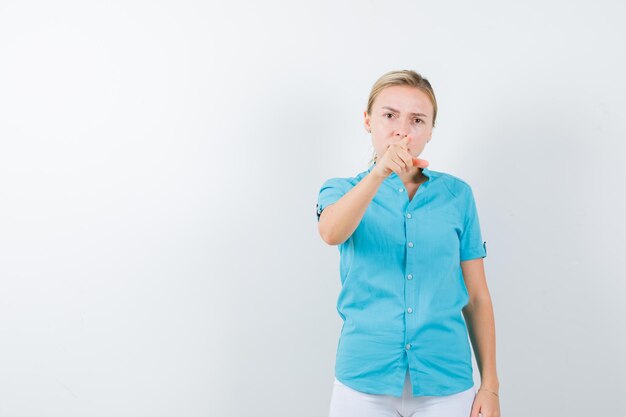 Femme blonde pointant vers la caméra en blouse bleue et à la grave