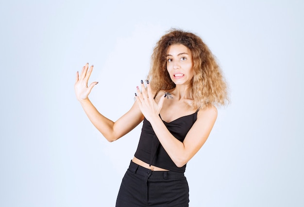 Femme blonde pointant vers le côté gauche et présentant quelque chose.