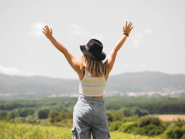 Femme blonde portant un chapeau avec ses mains vers le haut