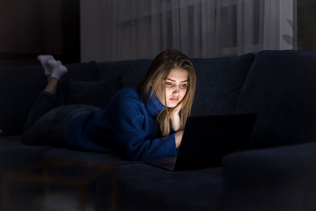 Femme blonde, pose divan, à, ordinateur portable