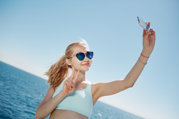 Femme blonde prenant selfie sur la plage