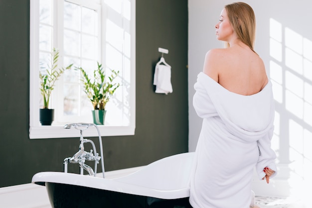 Femme blonde qui pose dans la salle de bain avec un peignoir