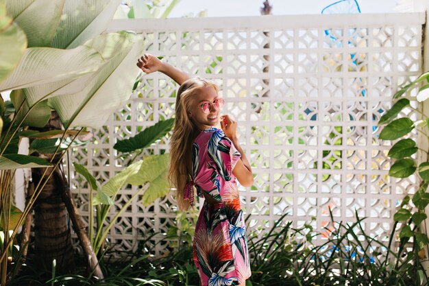 femme blonde regardant par-dessus l'épaule et riant sur fond de nature.