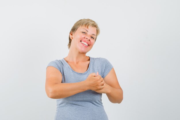 Femme blonde se frottant les mains en t-shirt bleu clair et à la vue de face, heureux.