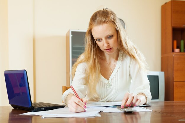 Femme blonde sérieuse remplit les documents