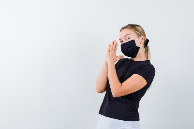 Femme blonde serrant les mains en position de prière en t-shirt noir