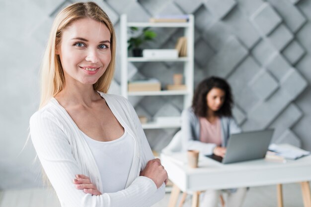 Femme blonde souriante et collègue ethnique qui travaille