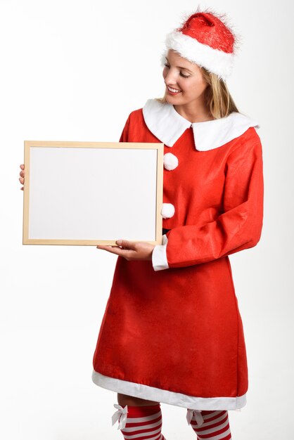 Femme blonde souriante dans les vêtements du père Noël avec tableau blanc