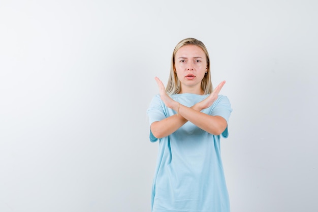 Femme blonde en t-shirt bleu tenant deux bras croisés