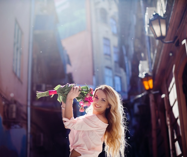 Femme Blonde Tient Un Bouquet De Pivoines Roses Posant Dans La Rue