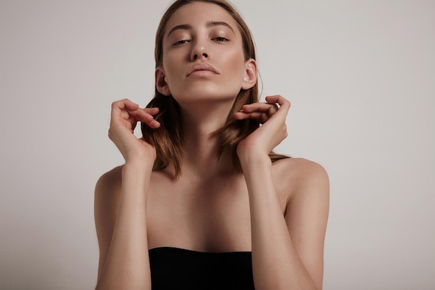 Femme blonde touchant ses cheveux et regardant la caméra