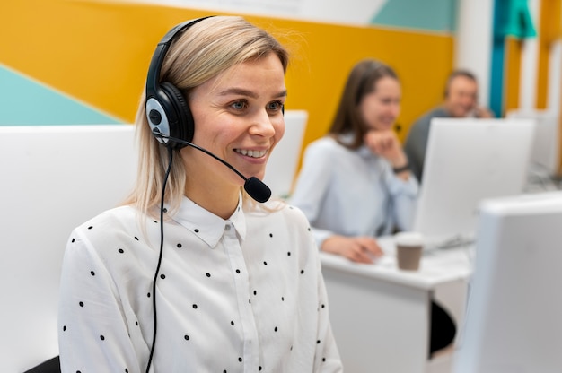 Photo gratuite femme blonde travaillant dans un centre d'appels avec casque et ordinateur