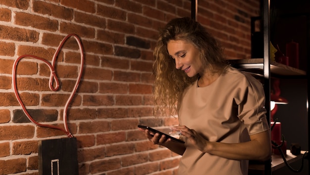 Femme blonde vérifiant son téléphone à la maison