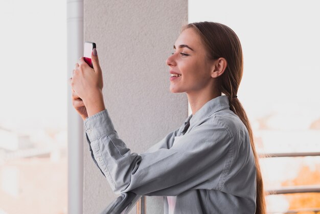 Femme blonde vue latérale à l'aide d'un téléphone