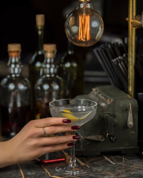 femme avec boisson alcoolisée garnie de peau de citron dans un verre à martini