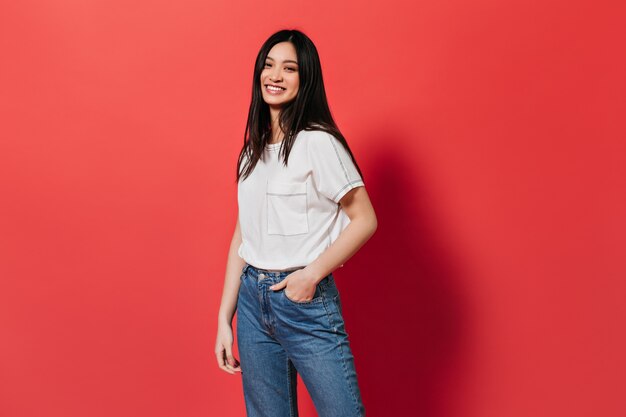 femme de bonne humeur, posant sur un mur rouge