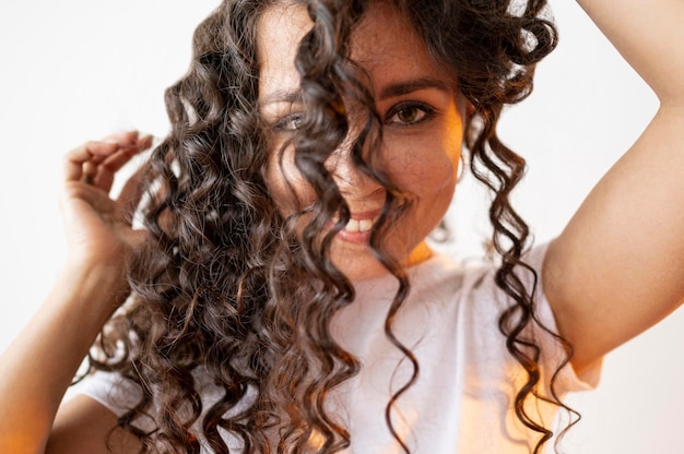 Photo gratuite femme bouclée jouant avec ses cheveux gros plan