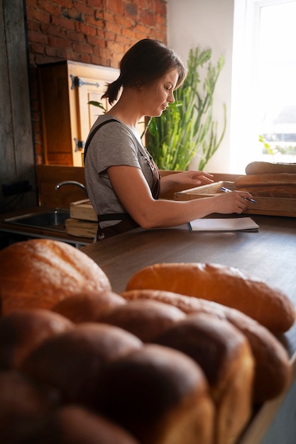 Photo gratuite femme boulangère prenant des notes à la pâtisserie