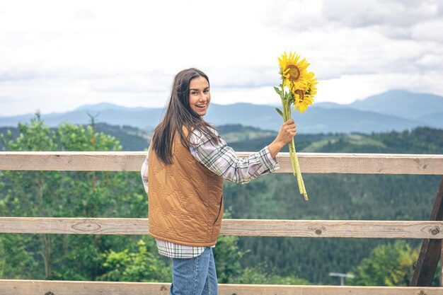 Femme avec un bouquet de tournesols dans la nature dans les montagnes