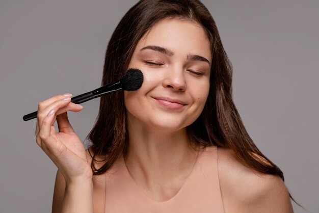 Femme brune à l'aide d'un pinceau à maquillage