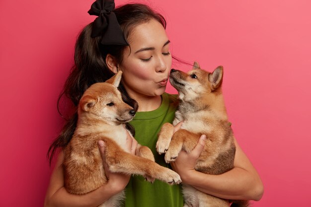 Femme brune asiatique embrasse les chiens avec amour, animaux de compagnie shiba inu, étant propriétaire responsable des animaux, passe ses loisirs à la maison