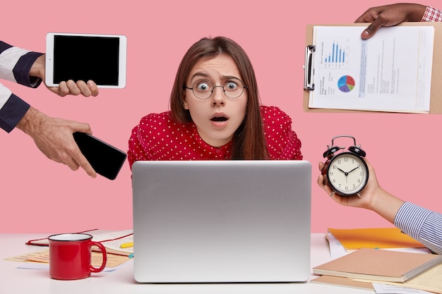 Femme brune assise au bureau entouré de gadgets et de papiers