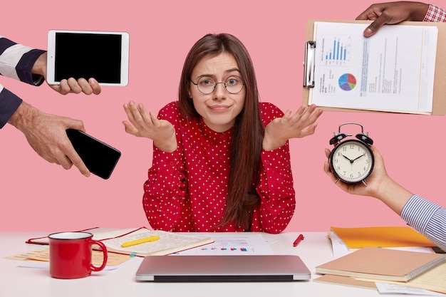 Femme brune assise au bureau entouré de gadgets et de papiers