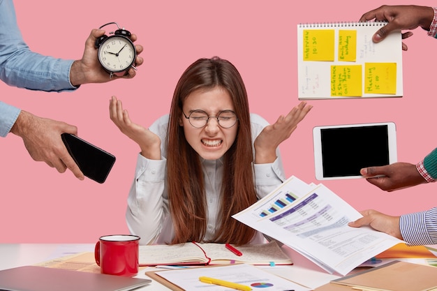 Femme brune assise au bureau entouré de gadgets et de papiers