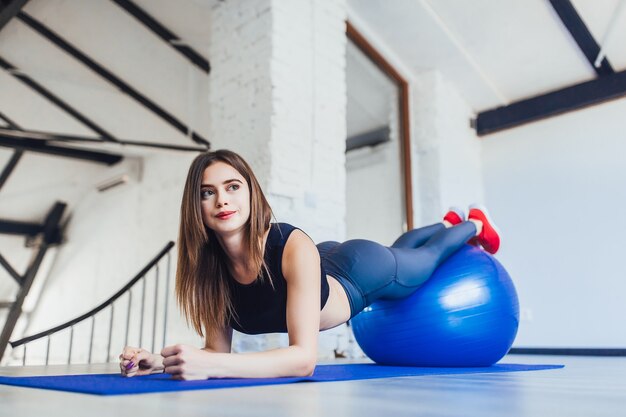 Femme brune athlétique faisant des exercices d'étirement à l'intérieur