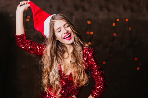 Femme brune aux cheveux longs décollant le chapeau de père Noël