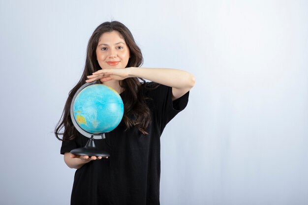 Femme brune aux cheveux longs tenant le globe terrestre et posant.