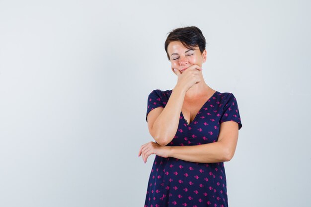 Femme Brune Ayant Mal Aux Dents En Robe à Motifs Violet Et Rouge Et à La Recherche D'épuisé. Vue De Face.