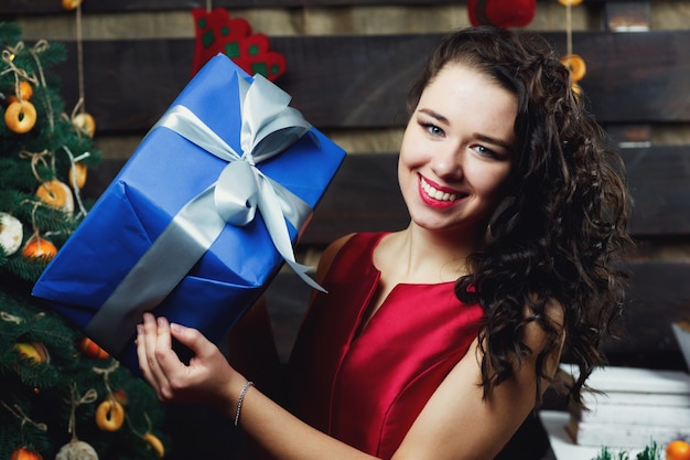 La femme brune bouclée tient la boîte présente bleue