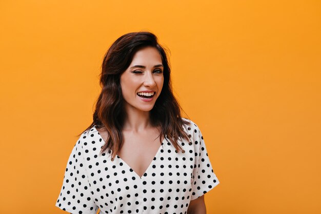 Femme brune en chemisier à pois clins d'oeil et sourires