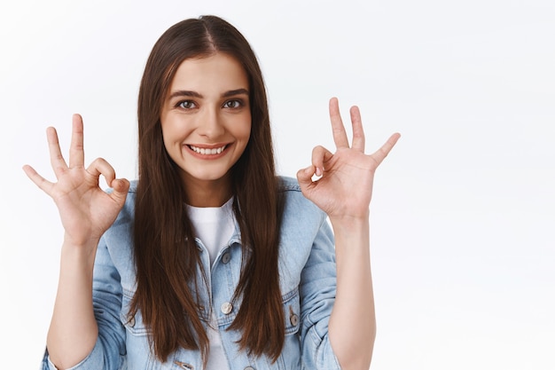 Femme brune confiante et optimiste, séduisante et affirmée, montrant un geste correct ou correct, donner une réponse positive, approuver quelque chose de génial, souriante vous encourage à faire un excellent choix