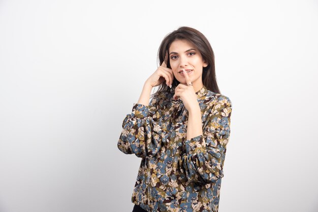 Femme brune debout sur un fond blanc.