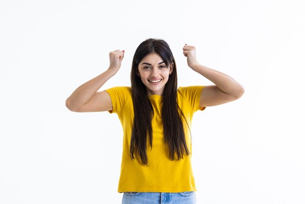 Femme brune faisant un geste gagnant heureux excité regardant les yeux fermés sur fond blanc