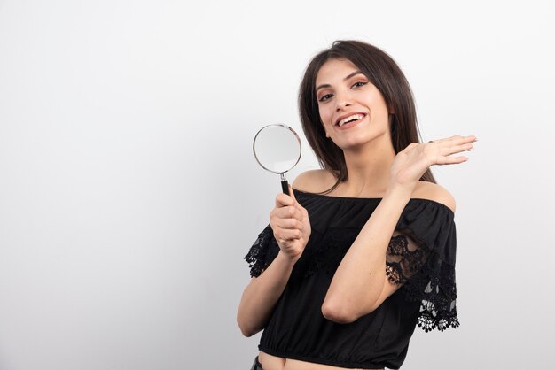 Femme brune posant avec une loupe.