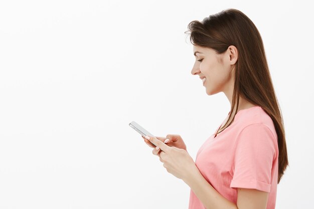 femme brune posant en studio avec son téléphone