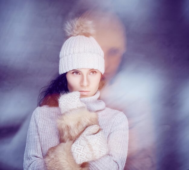 Femme brune en pull d'hiver chaud, gants de fourrure posant dans le brouillard.