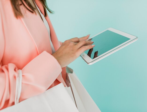 Femme brune avec tablette et sacs à provisions