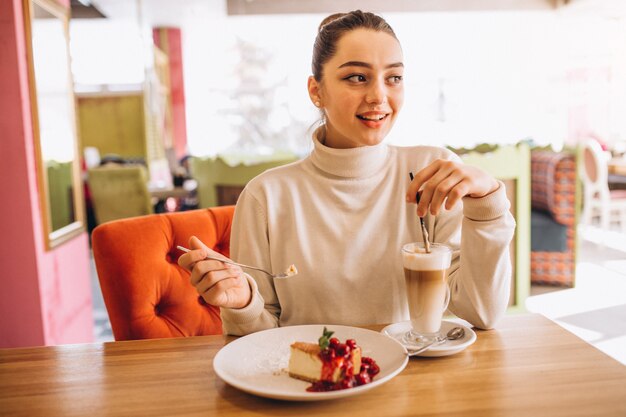 Femme buvant un café avec un dessert dans un café