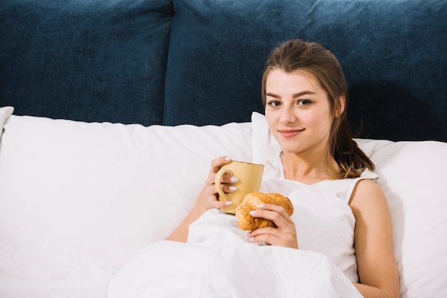 Photo gratuite femme buvant du café avec croissant au lit