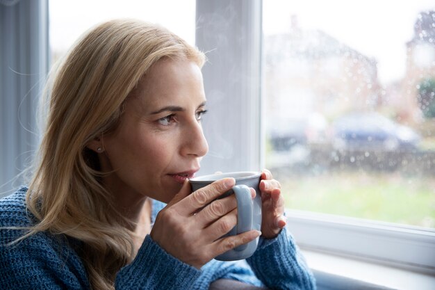 Femme buvant du thé pendant qu'il pleut